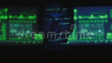 黑客程序员在计算机上工作，而绿色代码字符在网络安全中心反射他的脸